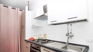 A compact kitchen with a gas stove, sink, and white cabinets. - The Casello sul Mare is a historic railway house built in 1895 as a residence for railway workers and restored in 2025 while preserving its authentic charm. The property is set in a truly unique position, suspended between the railway and the sea, offeri (Torremuzza)