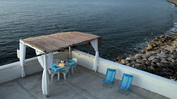 A covered outdoor seating area with a table and chairs, overlooking a body of water. - The Casello sul Mare is a historic railway house built in 1895 as a residence for railway workers and restored in 2025 while preserving its authentic charm. The property is set in a truly unique position, suspended between the railway and the sea, offeri (Torremuzza)
