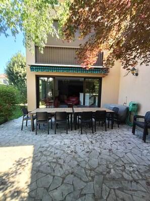 An outdoor patio area with a stone floor, a dining table with chairs, and a covered seating area. - Bright, spacious house with an enclosed plot offering complete privacy. (Saint-Girons)