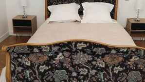 Ein Bett mit einem blumengemusterten Kopfteil, zwei Nachttische mit Lampen und ein Holzboden.