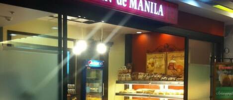 A bakery named "PAN de MANILA" with a display case of baked goods and a Pepsi refrigerator.