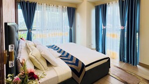 A bedroom with a bed, a bedside table with a vase of flowers, and a window with curtains. - Luxury Staycation beside Okada  (Parañaque)