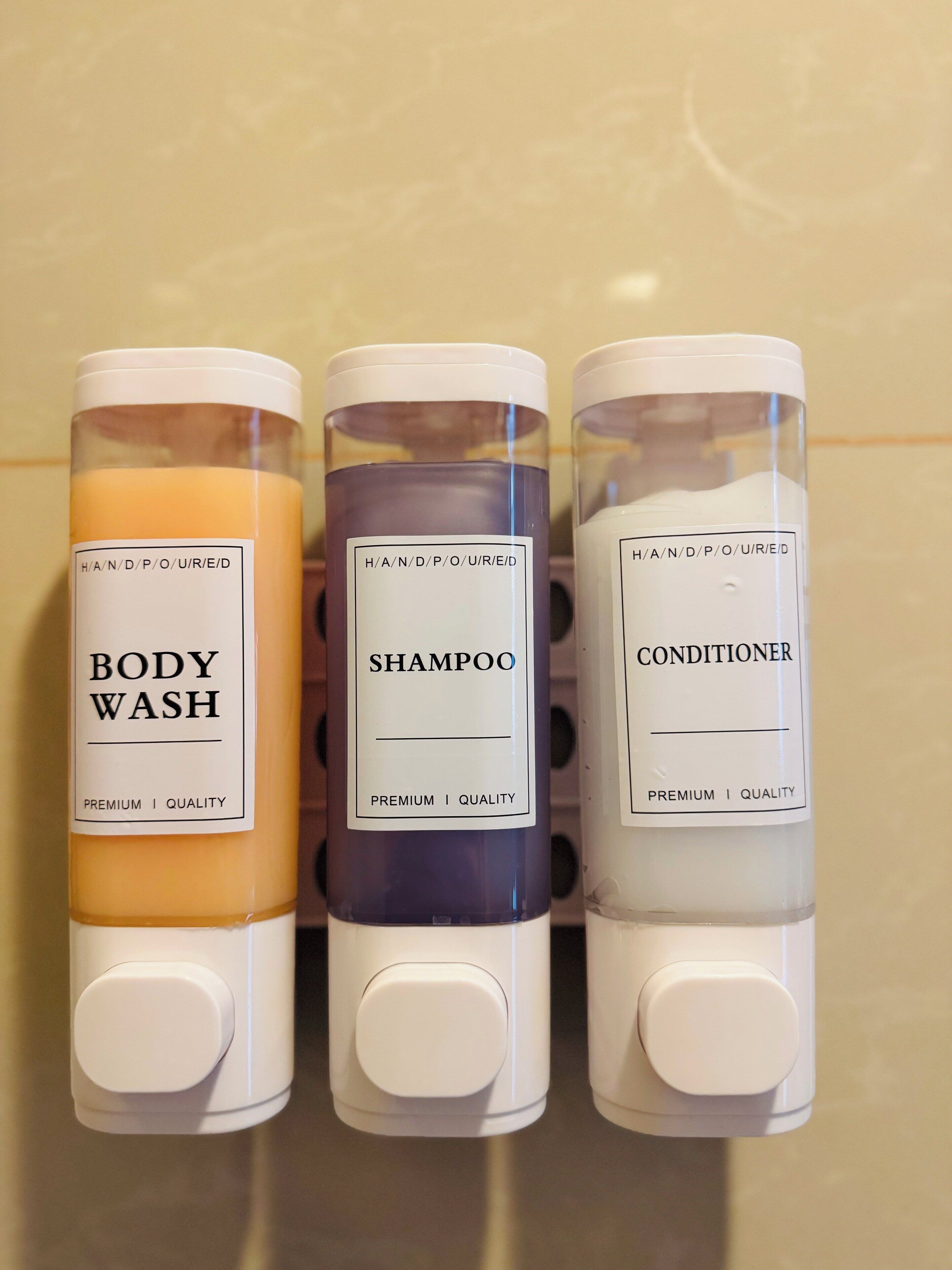 Trois flacons de gel douche, de shampoing et d’après-shampoing alignés.