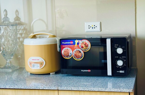 A Fujidenzo microwave oven and rice cooker on a kitchen counter. - Luxury Staycation beside Okada (Parañaque)