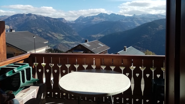 A balcony with a table and chairs, overlooking a mountainous landscape with buildings in the valley. - APARTMENT FACING MONT BLANC AND BEAUFORTAIN VALLEY (Villard-sur-Doron)