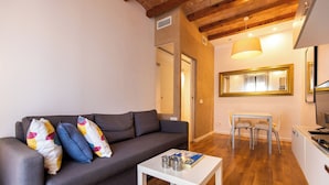 A modern living room with a grey sofa, a white coffee table, and a dining area with a table and chairs. - Tapioles: Nice apartment with balcony in Poble Sec (Poble Sec)