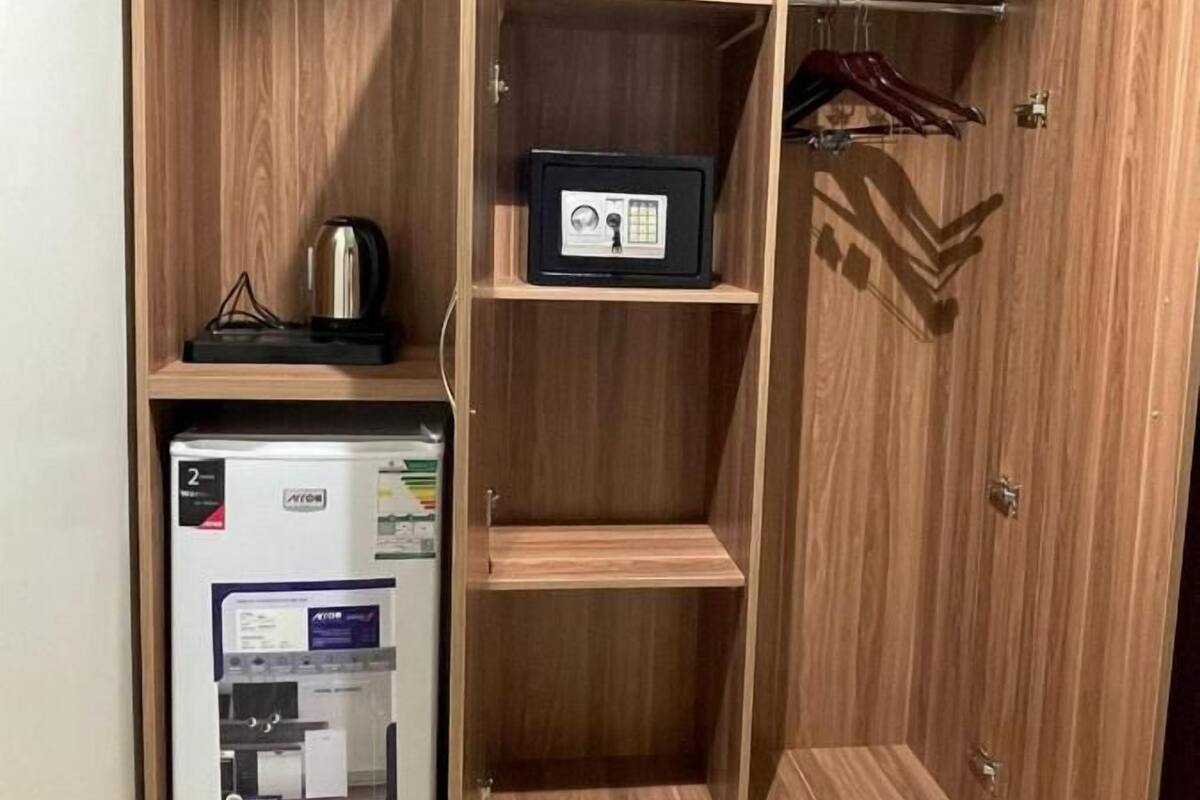 A walk-in closet with wooden shelving, a small refrigerator, and a safe.