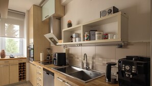 Une cuisine moderne équipée d’un évier à deux bacs, d’une machine à café et d’un four encastré.