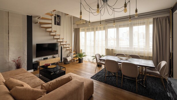 Un salon moderne comprenant un canapé, un téléviseur et un coin repas avec des chaises et une table.