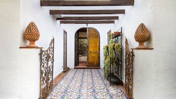 A hallway with patterned tile flooring, a wooden ceiling, and decorative urns on pedestals.