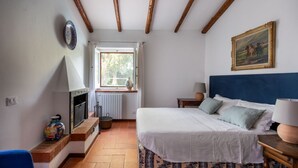 Une chambre à coucher avec un lit, une fenêtre, une cheminée et un tableau au mur.