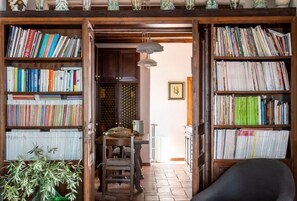 Une pièce avec une bibliothèque en bois remplie de livres, une table à manger avec des chaises et une plante en pot.