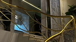 A modern interior with a golden spiral staircase, marble columns, and a ceiling with recessed lighting. - Rox luxury Hotel (Taif)