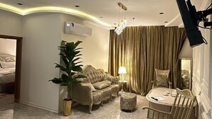 A spacious living room with a marble floor, a sofa set, a dining table with chairs, and a chandelier. - Rox luxury Hotel (Taif)