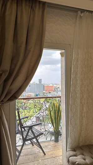 A room with a view of a cityscape through a large window with curtains.