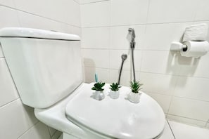 A white toilet with a tank, a bidet, and a toilet paper holder.