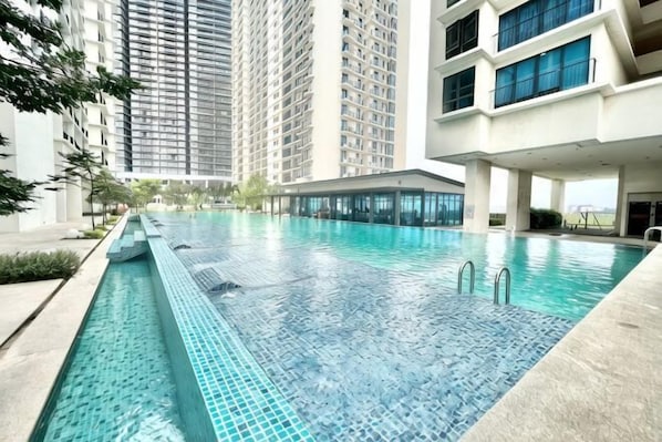 A swimming pool with clear blue water, surrounded by high-rise buildings.