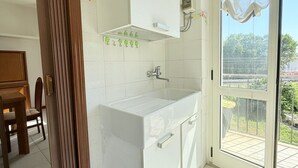 A kitchen with white cabinets, a sink, and a window overlooking a garden. - SE183 - Senigallia, comfortable three-room apartment 100 meters from the sea (Senigallia)