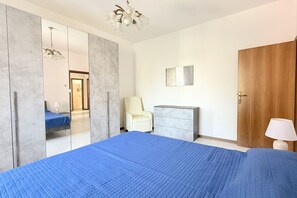 Une chambre à coucher avec un grand lit, une armoire, un bureau, une chaise et une porte.