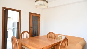 A dining area with a wooden table and chairs, a sofa with cushions, a wooden door, and a ceiling light fixture. - SE183 - Senigallia, comfortable three-room apartment 100 meters from the sea (Senigallia)