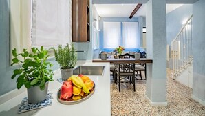 A modern kitchen with a central island, a dining area, and a staircase leading to an upper level. - House with canal view (Venezia)