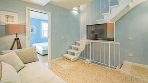 A modern living room with a sofa, a lamp, a television, and a staircase. - House with canal view (Venezia)