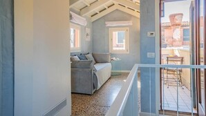 A cozy room with a grey sofa, a small table, and a window with a view of the outside. - House with canal view (Venezia)