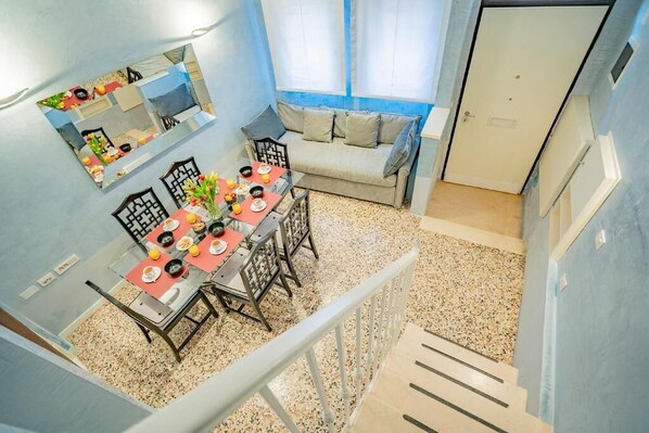 A dining area with a table set for four, a sofa, and a window with curtains. - House with canal view (Venezia)