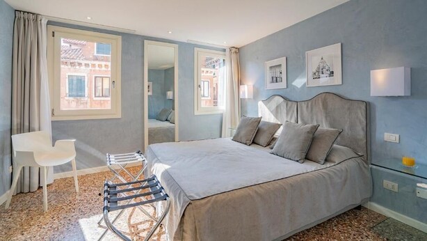 A bedroom with a bed, a chair, a small table, and a mirror. - House with canal view (Venezia)