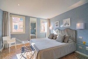 Une chambre à coucher avec un lit, une chaise, une petite table et un miroir.