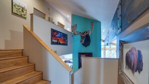 Una escalera de madera con una pared verde azulado y una cabeza de alce montada.