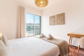 A hotel room with a large bed, a desk, a chair, a window with curtains, and artwork on the wall. - Lido Vista Apartment by Atlantic Holiday (Funchal)