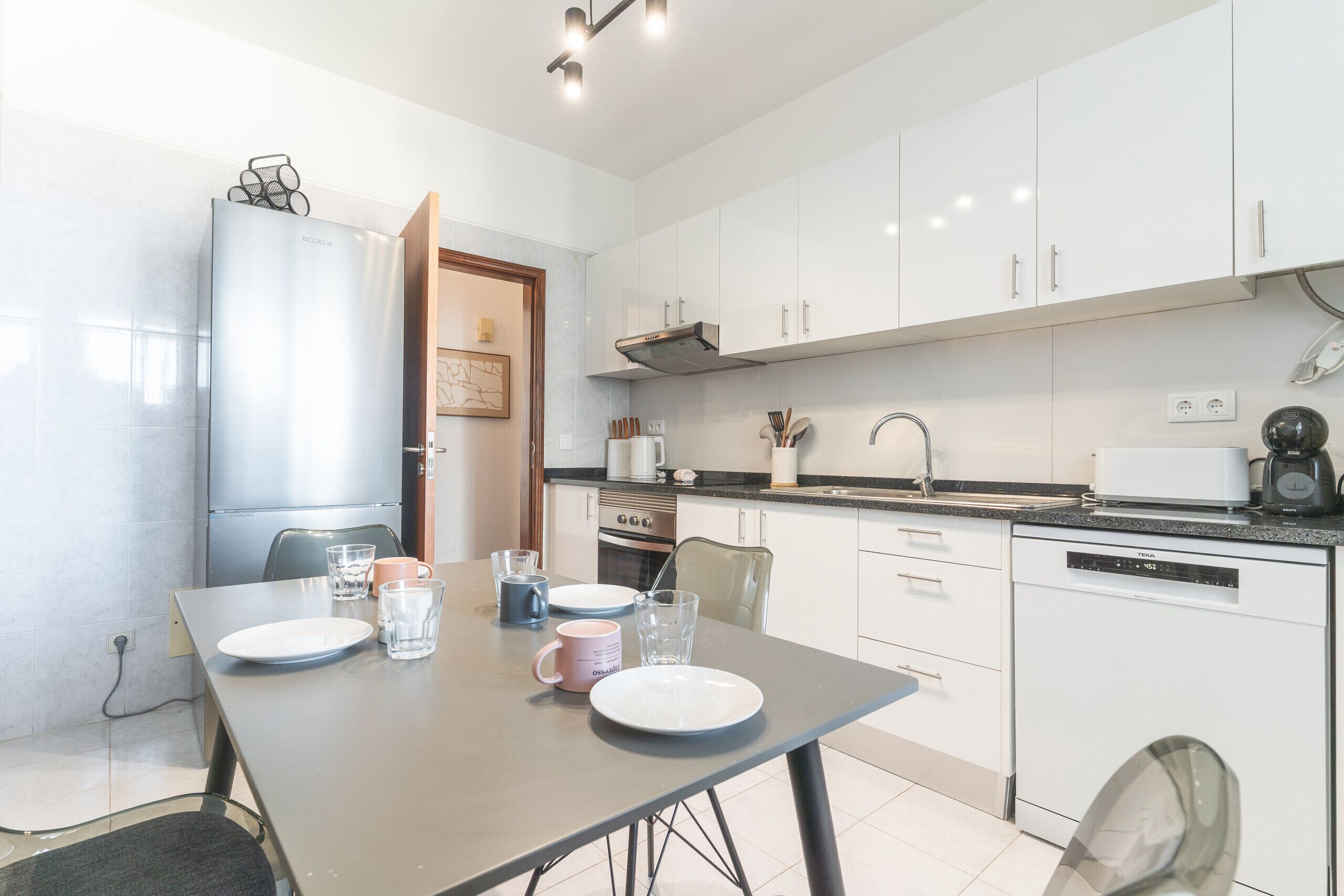 A modern kitchen with white cabinets, a built-in oven, and a dishwasher.