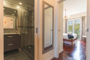 Ein Hotelzimmer mit Dusche, Bett, Nachttisch und Blick nach außen.