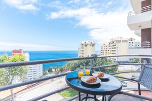Ein Balkon mit Tisch, zwei Tellern mit Croissants und zwei Gläsern Orangensaft.