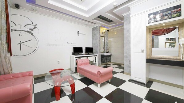 A hotel room with a checkered floor, a pink sofa, a glass coffee table, a TV, and a clock on the wall. - From H Rubens Hotel Mokpo Pyeonghwa Square (Mokpo)