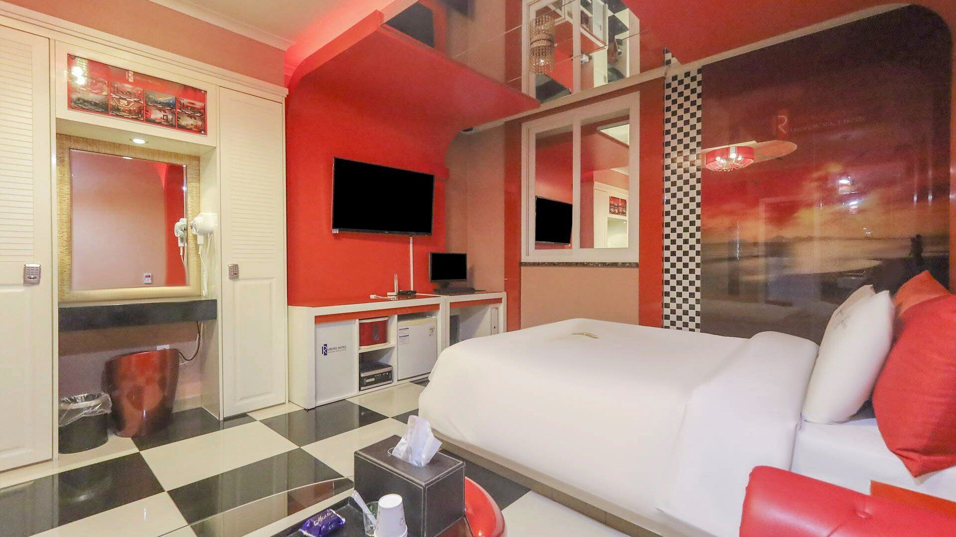 Una habitación de hotel con una cama grande, televisión, escritorio y baño.
