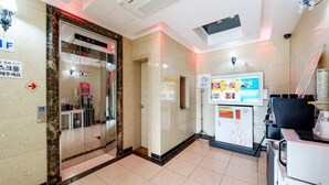 A hotel lobby with a reception desk, a glass elevator, and a digital information board. - From H Rubens Hotel Mokpo Pyeonghwa Square (Mokpo)