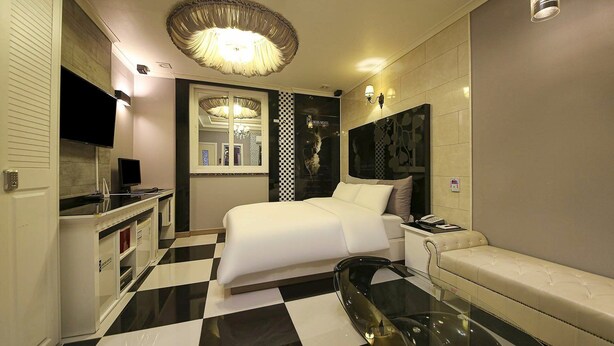A hotel room with a checkered floor, a bed, a glass table, a sofa, a TV, and a minibar. - From H Rubens Hotel Mokpo Pyeonghwa Square (Mokpo)