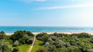 A coastal landscape with a beach, dense greenery, and a clear sky. - Residence Belvedere (Lido Adriano)