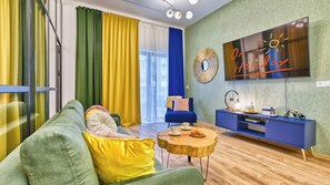 A modern living room with a green sofa, a blue armchair, a wooden coffee table, and a blue TV stand. - Apartamenty Żródło Izery - by OnHoliday (Świeradów-Zdrój)