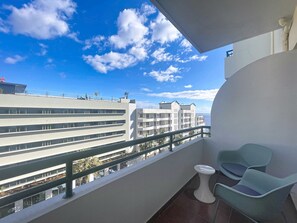 En balkon med udsigt over et moderne bykompleks, et lille bord og to stole.