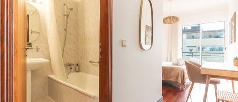 A modern bathroom with a bathtub, shower, and a toilet.