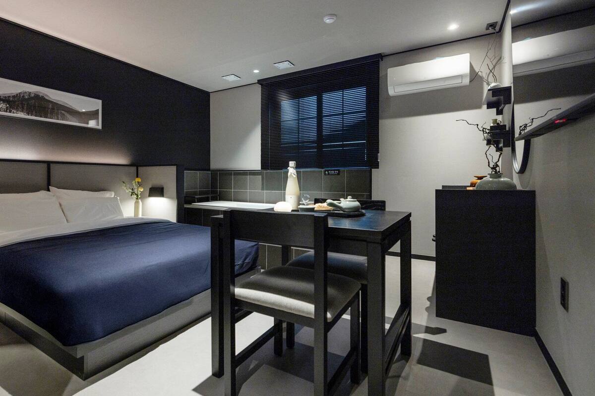 Ein modernes Hotelzimmer mit Bett, Schreibtisch und einem Fenster mit Jalousien.