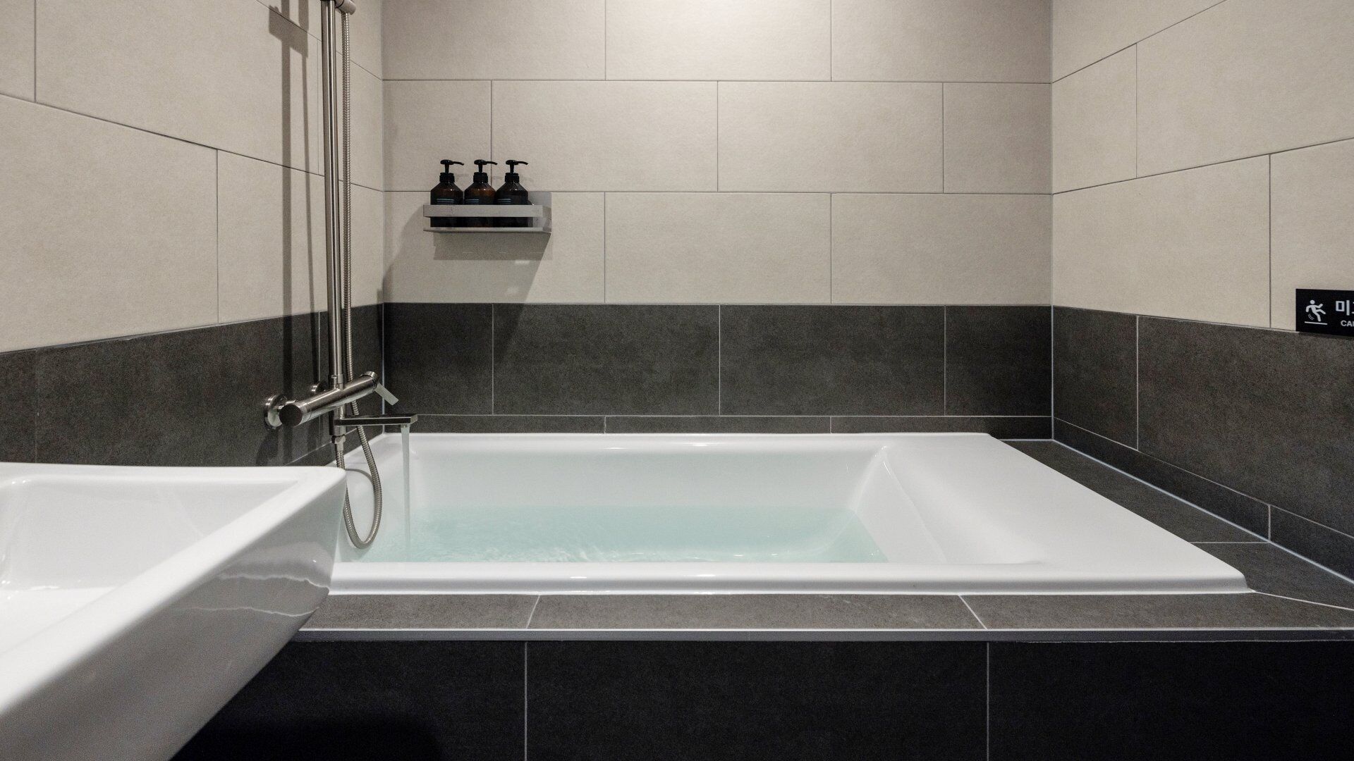 Un baño moderno con una bañera grande, ducha y un estante con artículos de aseo.