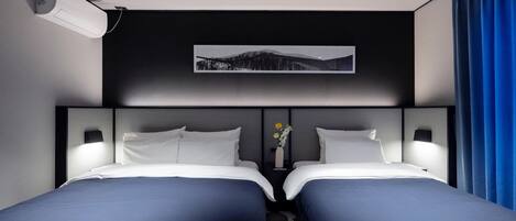 Habitación de hotel con dos camas, aire acondicionado instalado, un cuadro enmarcado en la pared y una cortina azul.