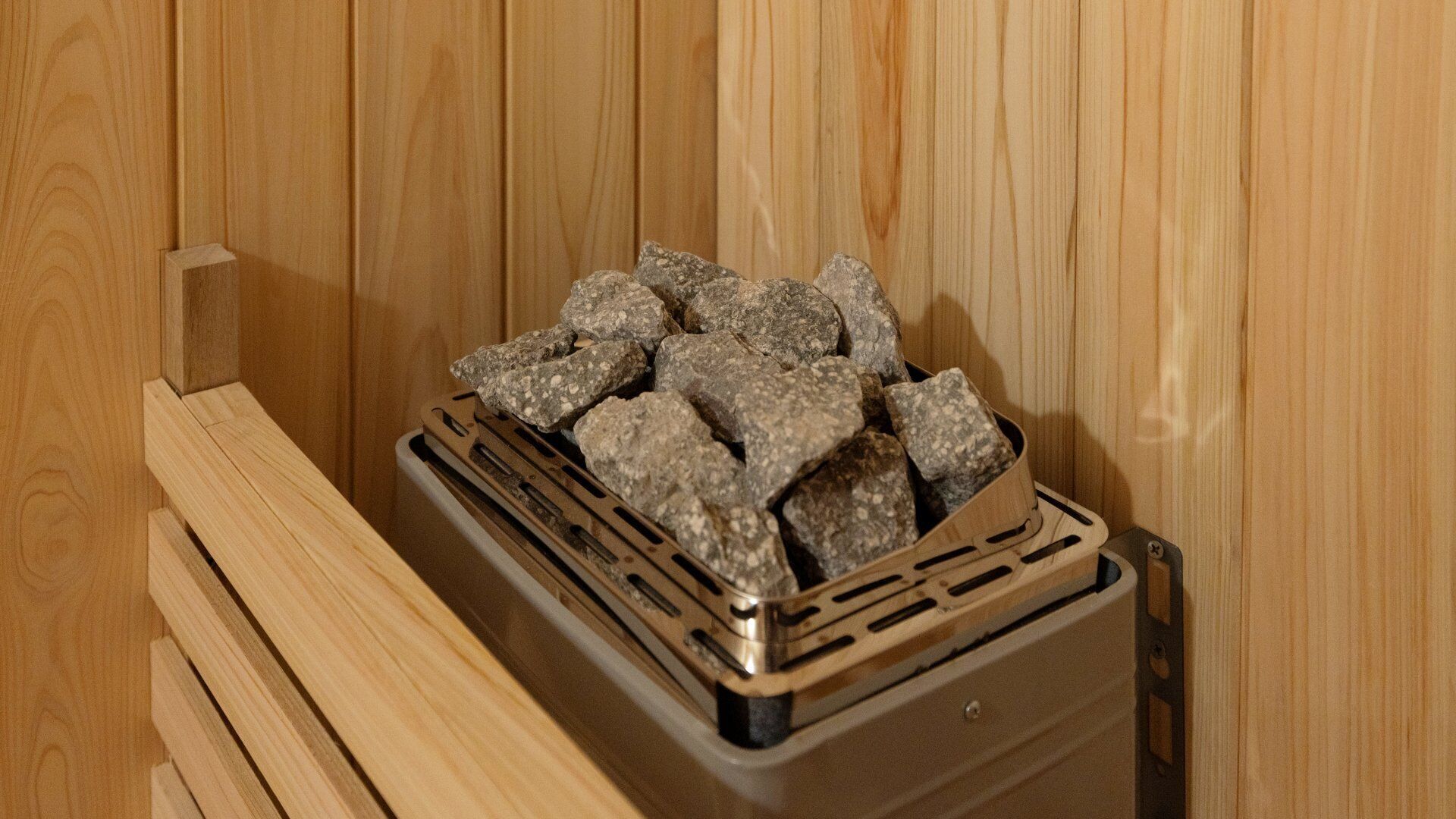 Een sauna met houten wanden en een metalen bak met stenen.