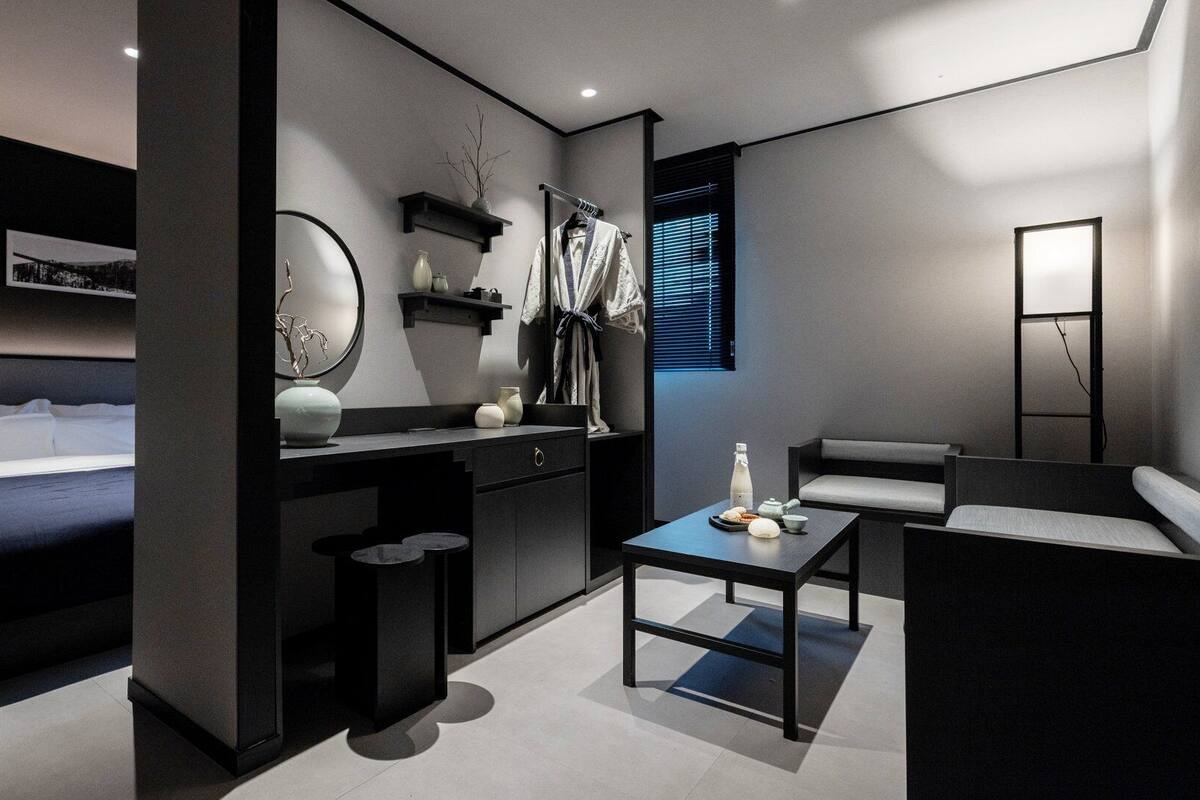 Ein modernes Hotelzimmer mit einem Bett, einem Schreibtisch, einem Stuhl und einem kleinen Tisch mit Tee-Service.