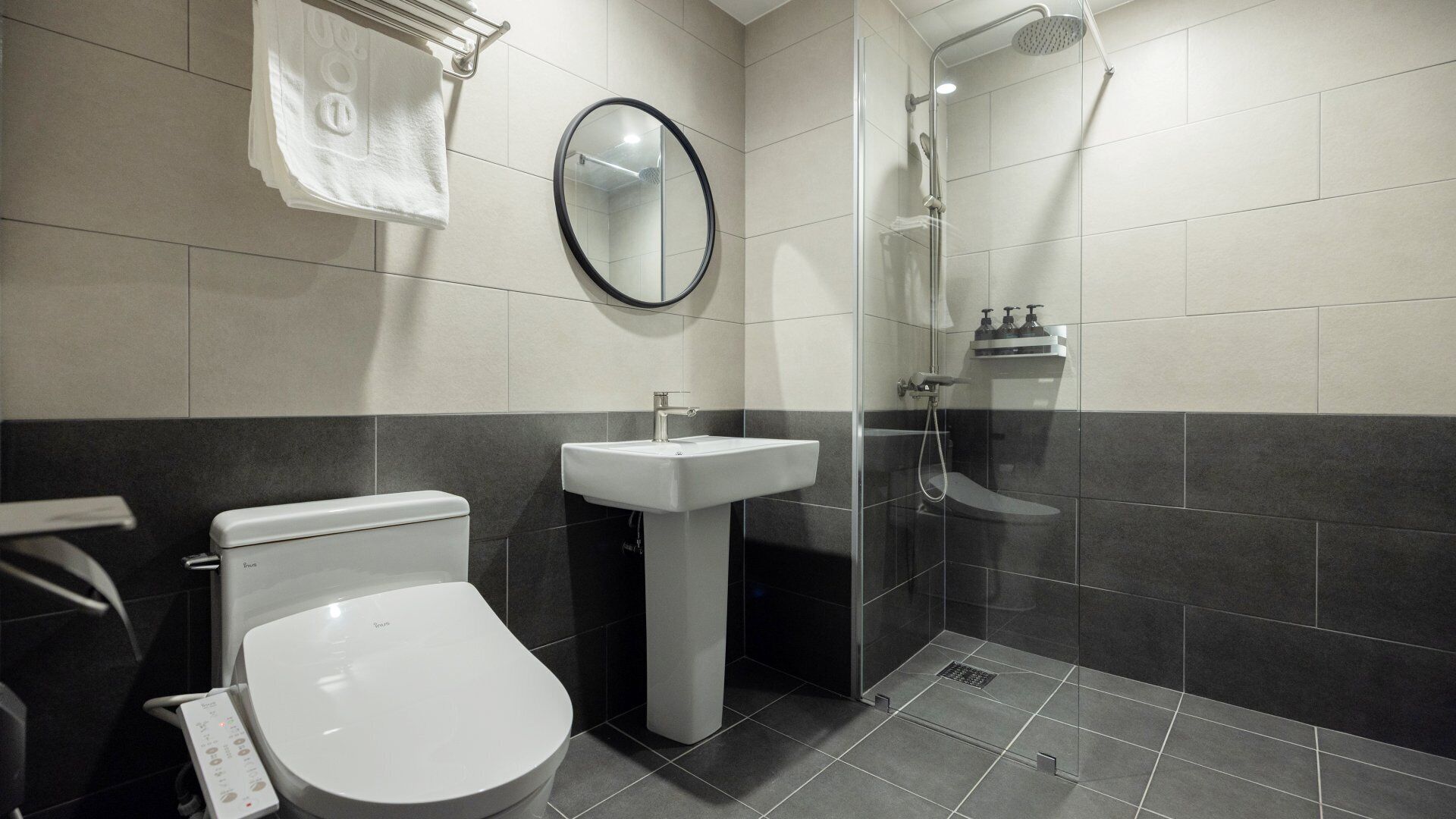 A modern bathroom with a toilet, sink, and glass-enclosed shower.