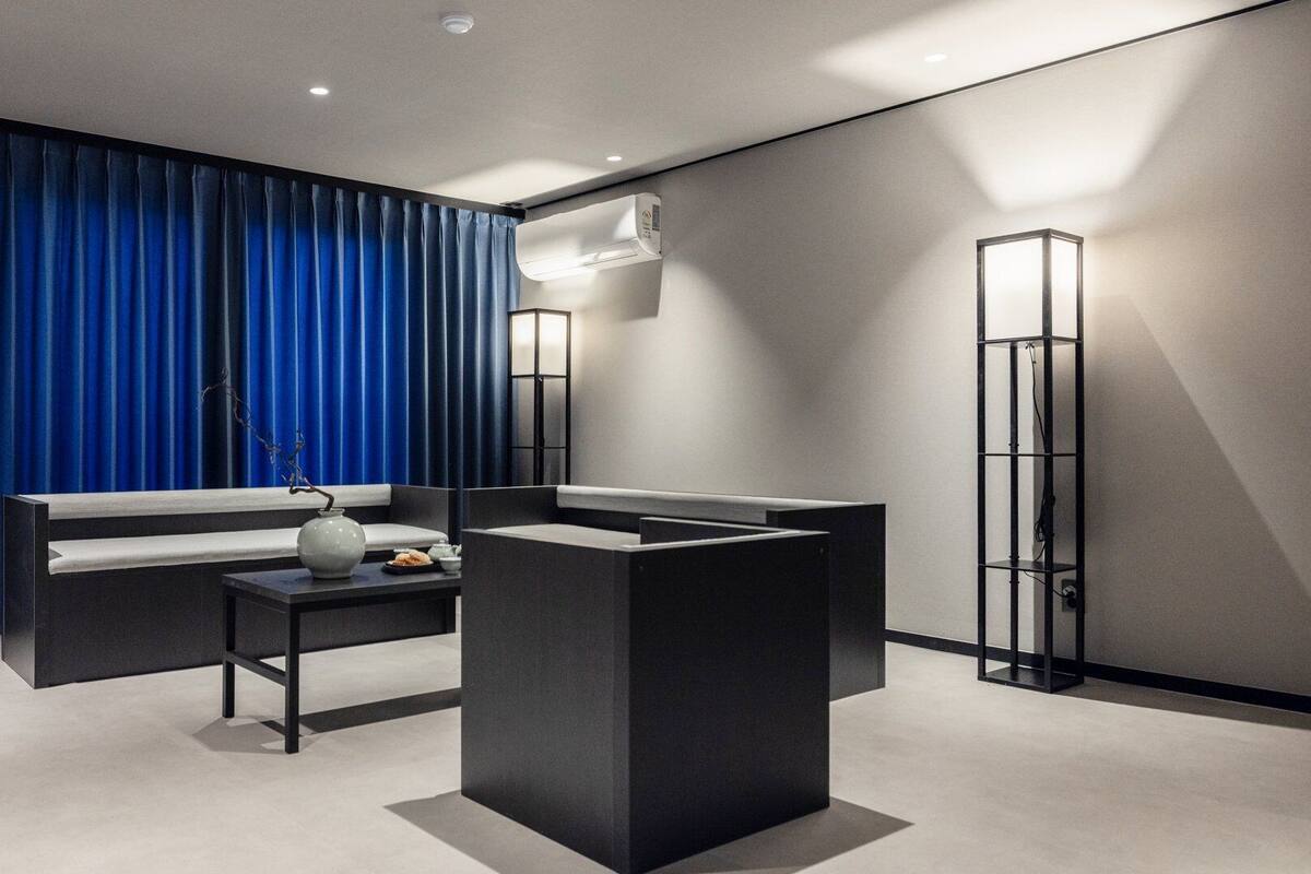 Ein modernes Zimmer mit einer Couch, einem kleinen Tisch mit einer Vase und einer hohen Stehlampe.